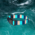 Blue Stripe padded dog collar with navy, turquoise and sand stripes displayed over an ocean background.