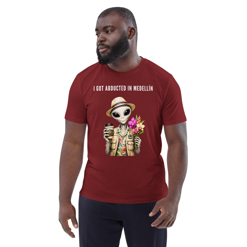 I Got Abducted in Medellin alien T-shirt in burgundy, worn by a model with dark trousers, three-quarter view.