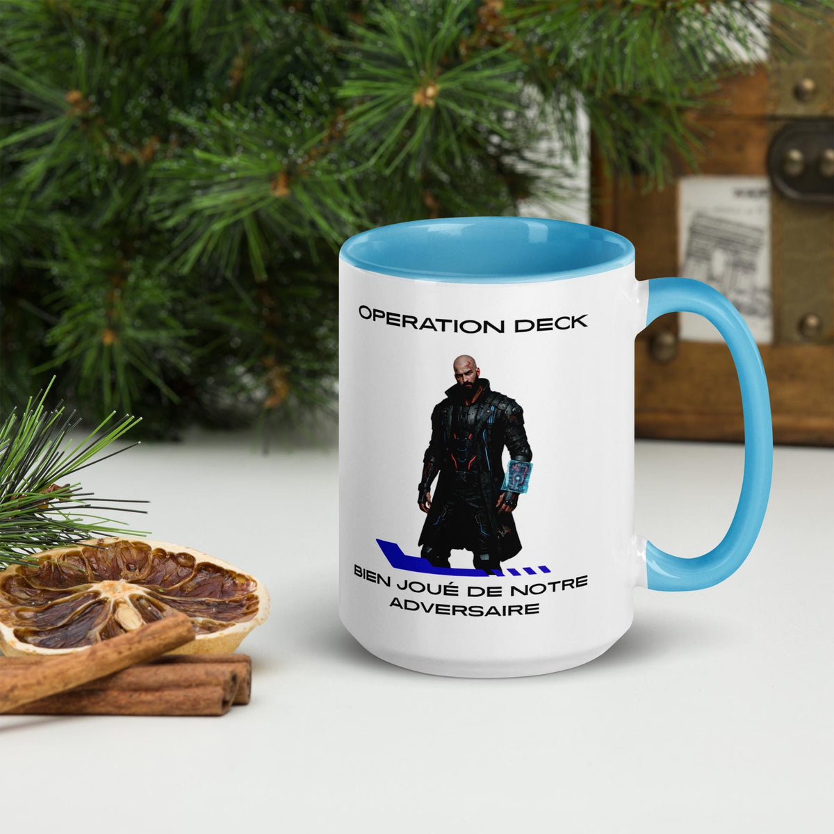 Operation Deck Bien Joué mug character and quote side beside evergreen branches and cinnamon.