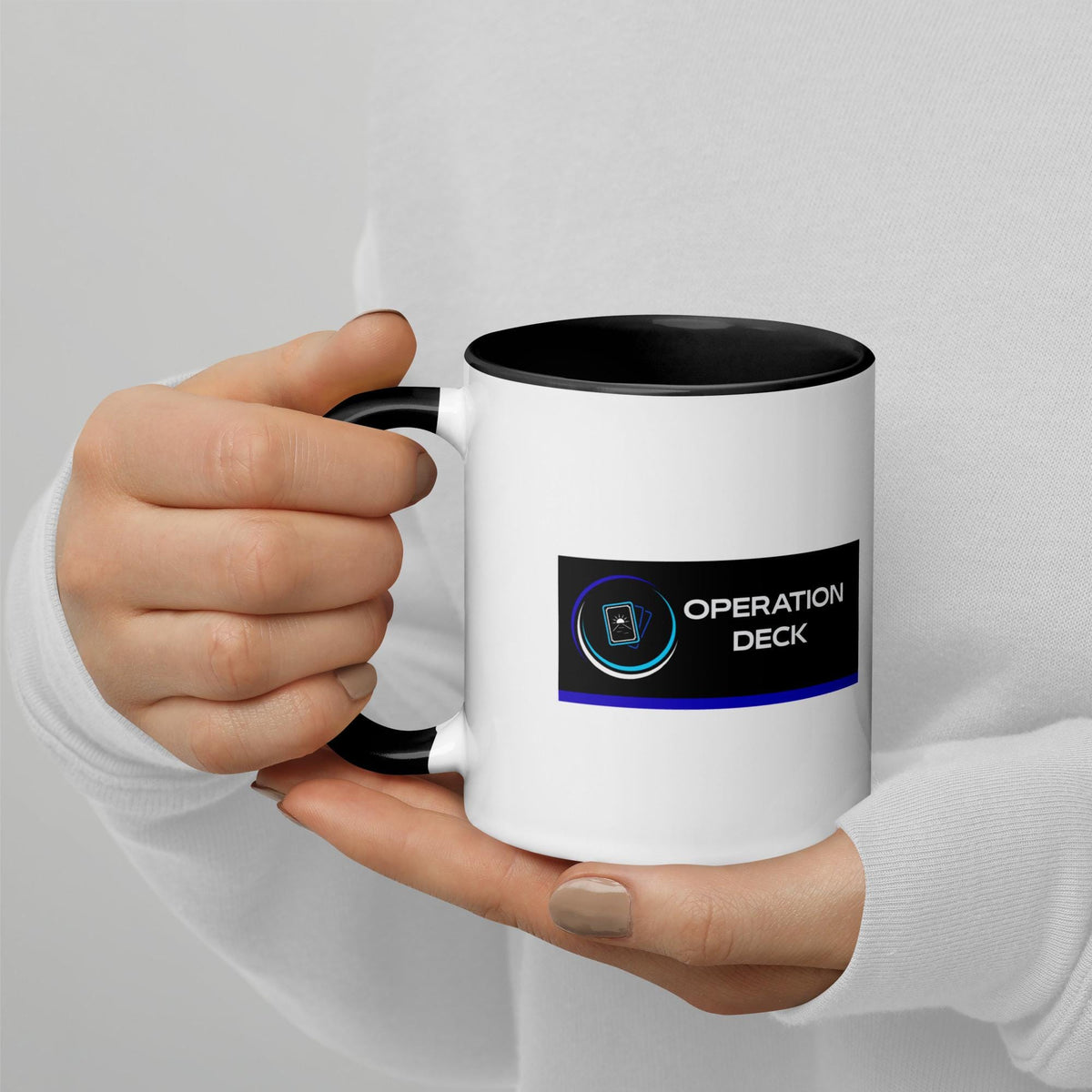 Operation Deck Désagréable mug logo side held in both hands against a white top.
