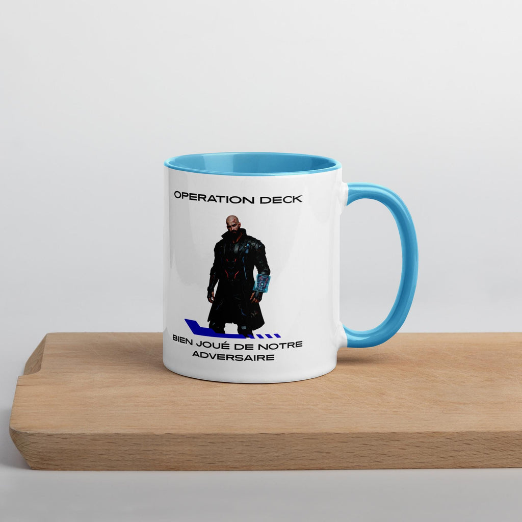 Operation Deck Bien Joué mug character and quote side on a wooden shelf, cyan handle to the right.