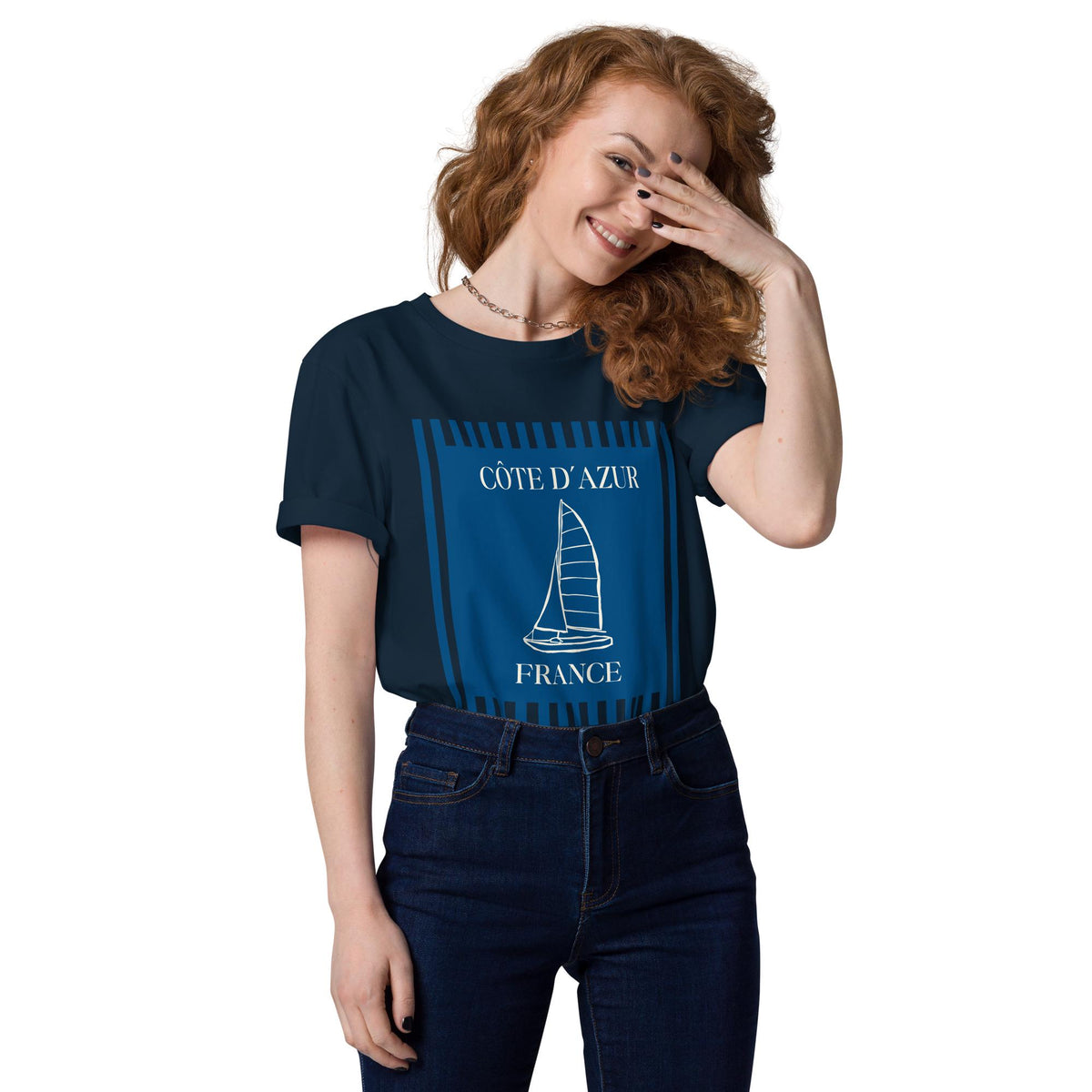 Côte d'Azur sailboat T-shirt in navy, worn by a model with one hand raised to the face.