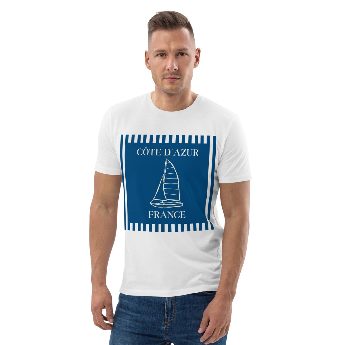 Côte d'Azur sailboat T-shirt in white, worn by a model with hands in pockets on white.