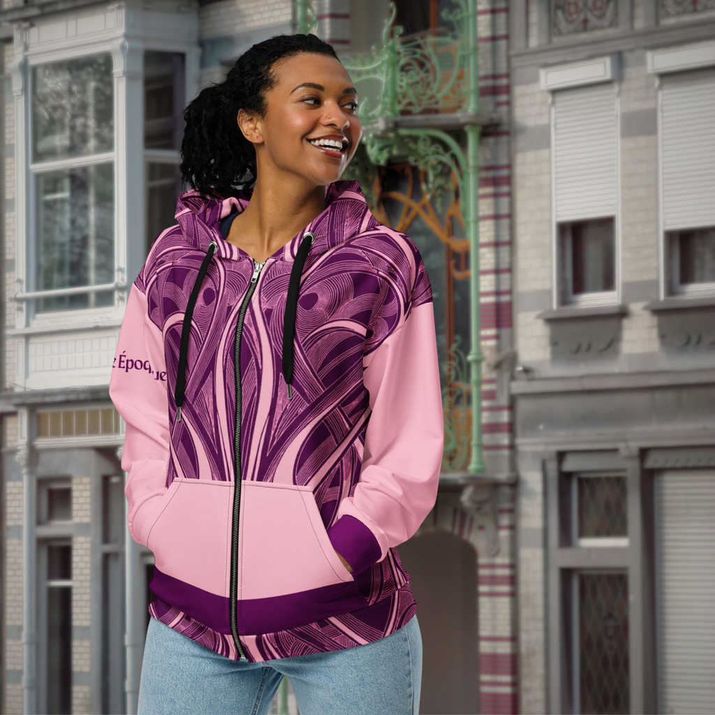 Pink Art Nouveau zip hoodie worn with jeans on a city street, front three-quarter view.