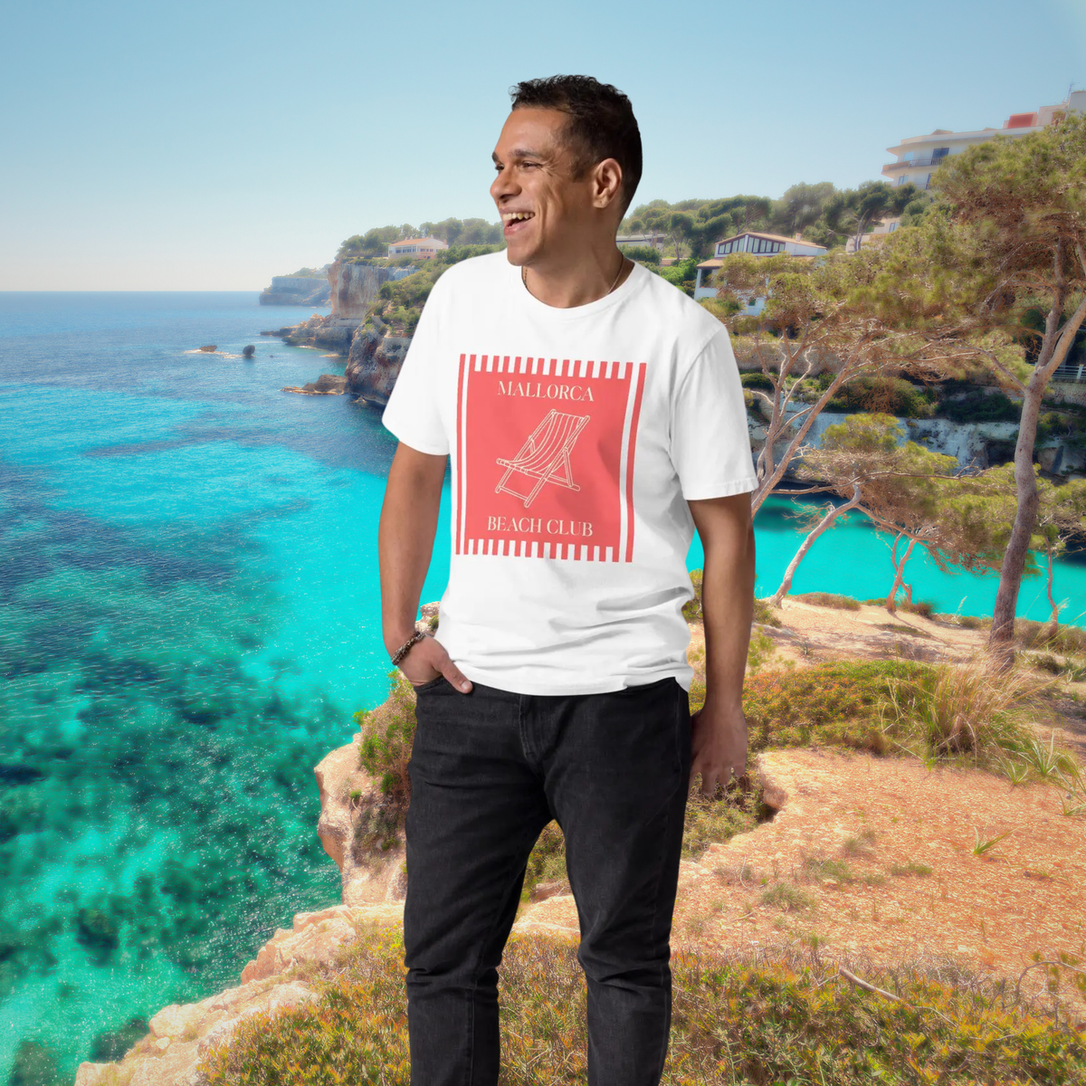Mallorca Beach Club T-shirt in white, full-length view on a model against turquoise coastal waters.