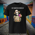 I Got Abducted in Medellin alien T-shirt in black, front product view of the tropical alien against a colorful street.