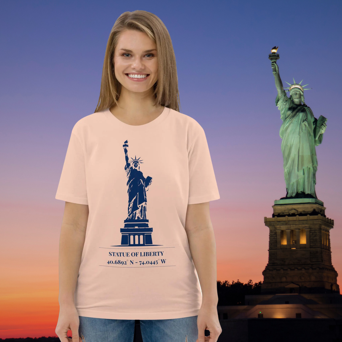 Statue of Liberty coordinates T-shirt in peach, worn by a model against a Statue of Liberty sunset backdrop.