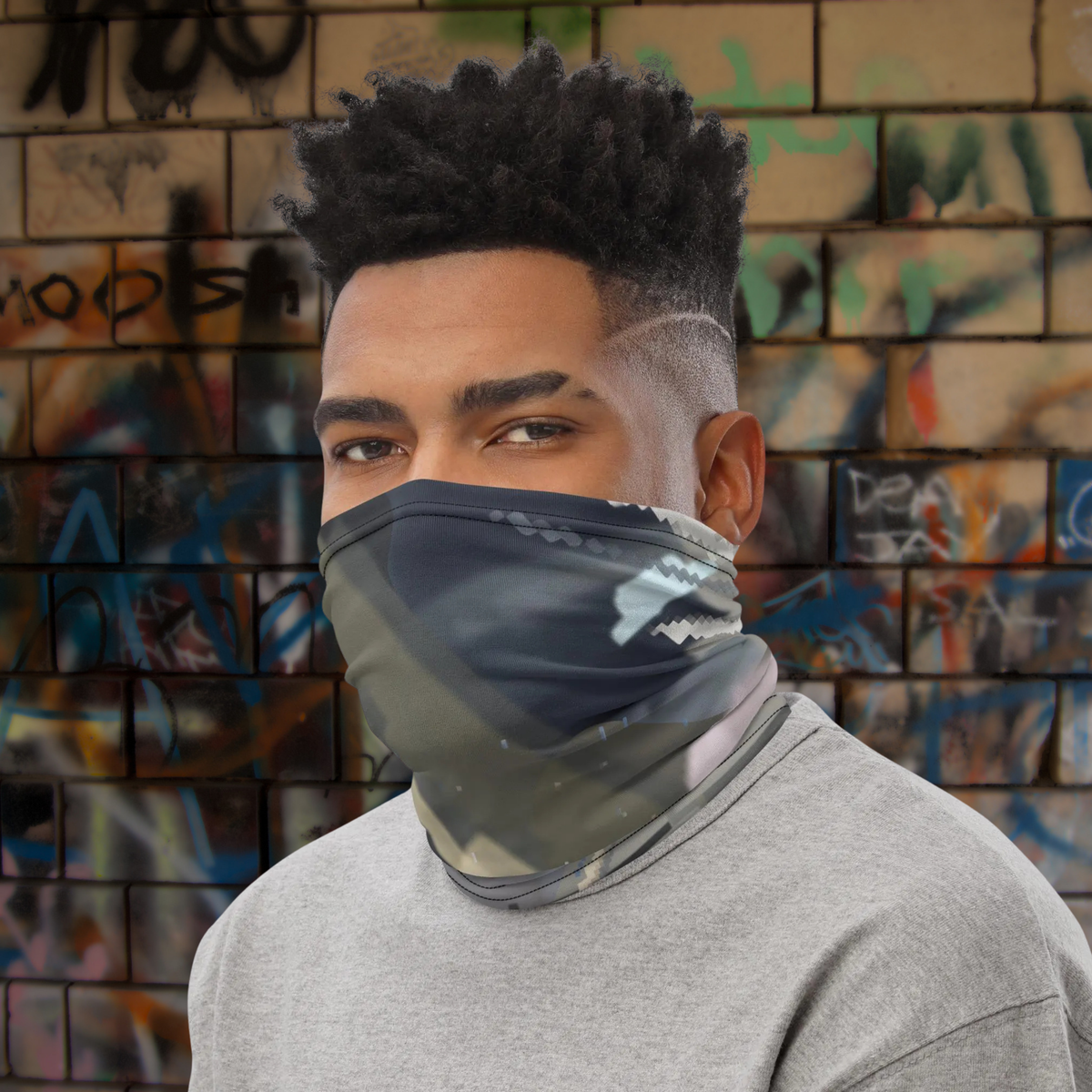 Urban Concrete 4 neck gaiter worn as a face covering beside a graffiti-covered wall.