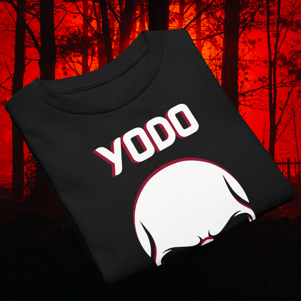 Folded black YODO skull T-shirt shown against a red forest background.