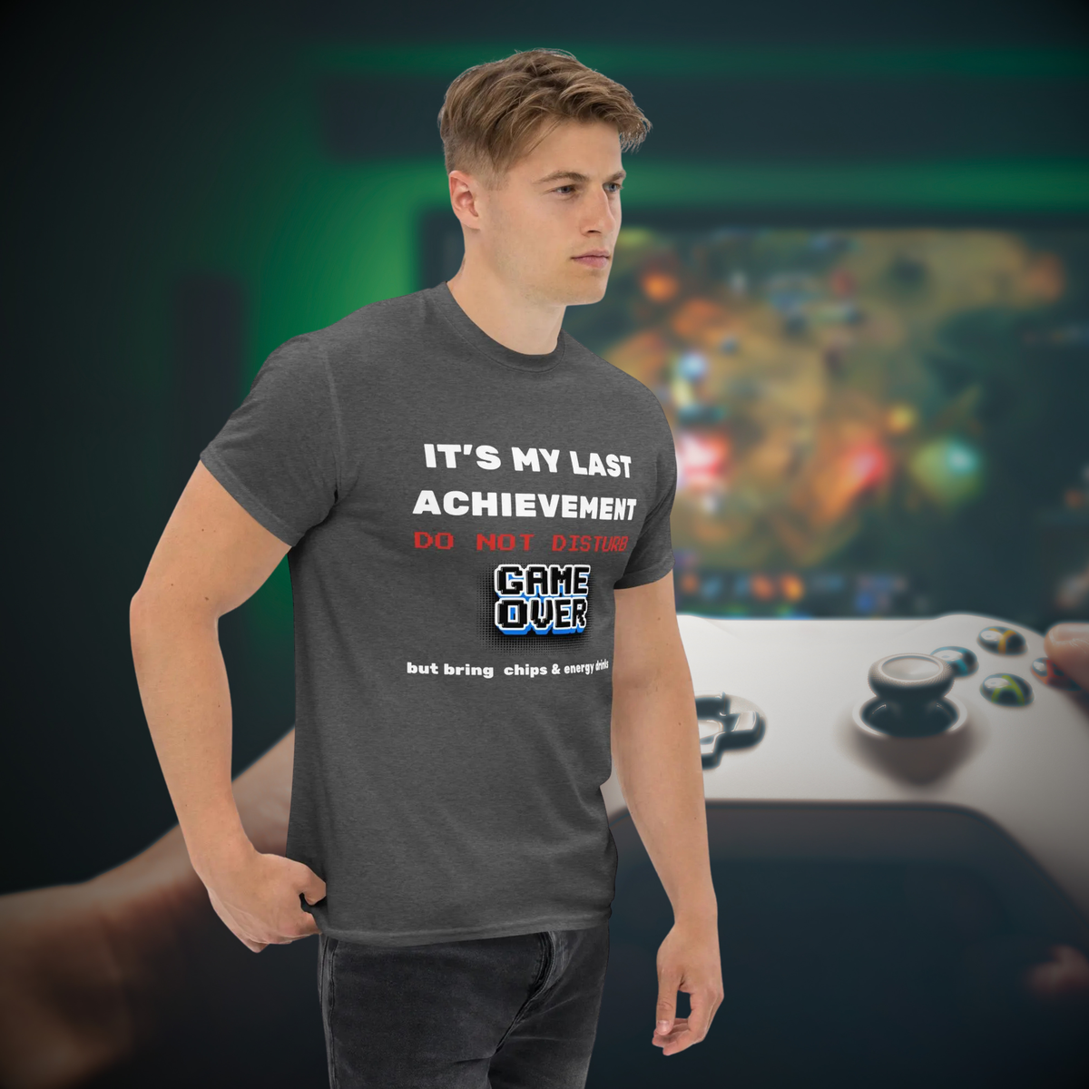 It's My Last Achievement gamer T-shirt in dark heather grey, worn by a model beside a game controller backdrop.
