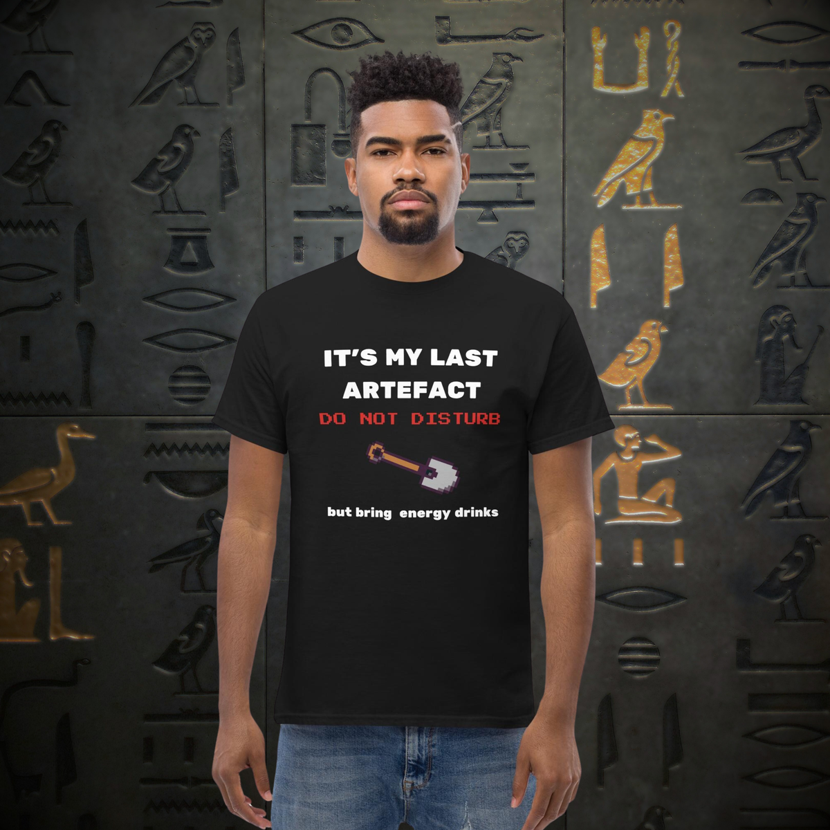 It's My Last Artefact gamer T-shirt in black, worn by a model against a stone carving backdrop.