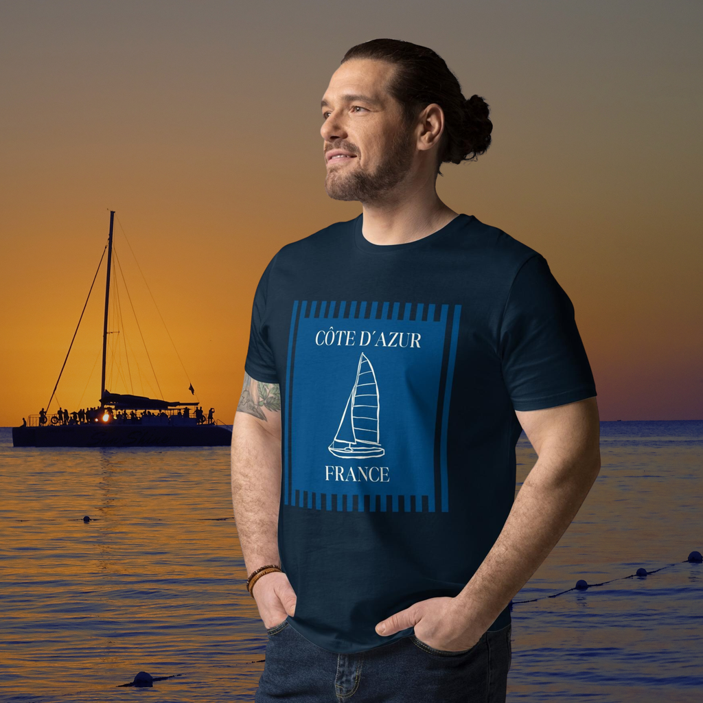 Côte d'Azur sailboat T-shirt in navy, worn by a model against a sailing sunset.