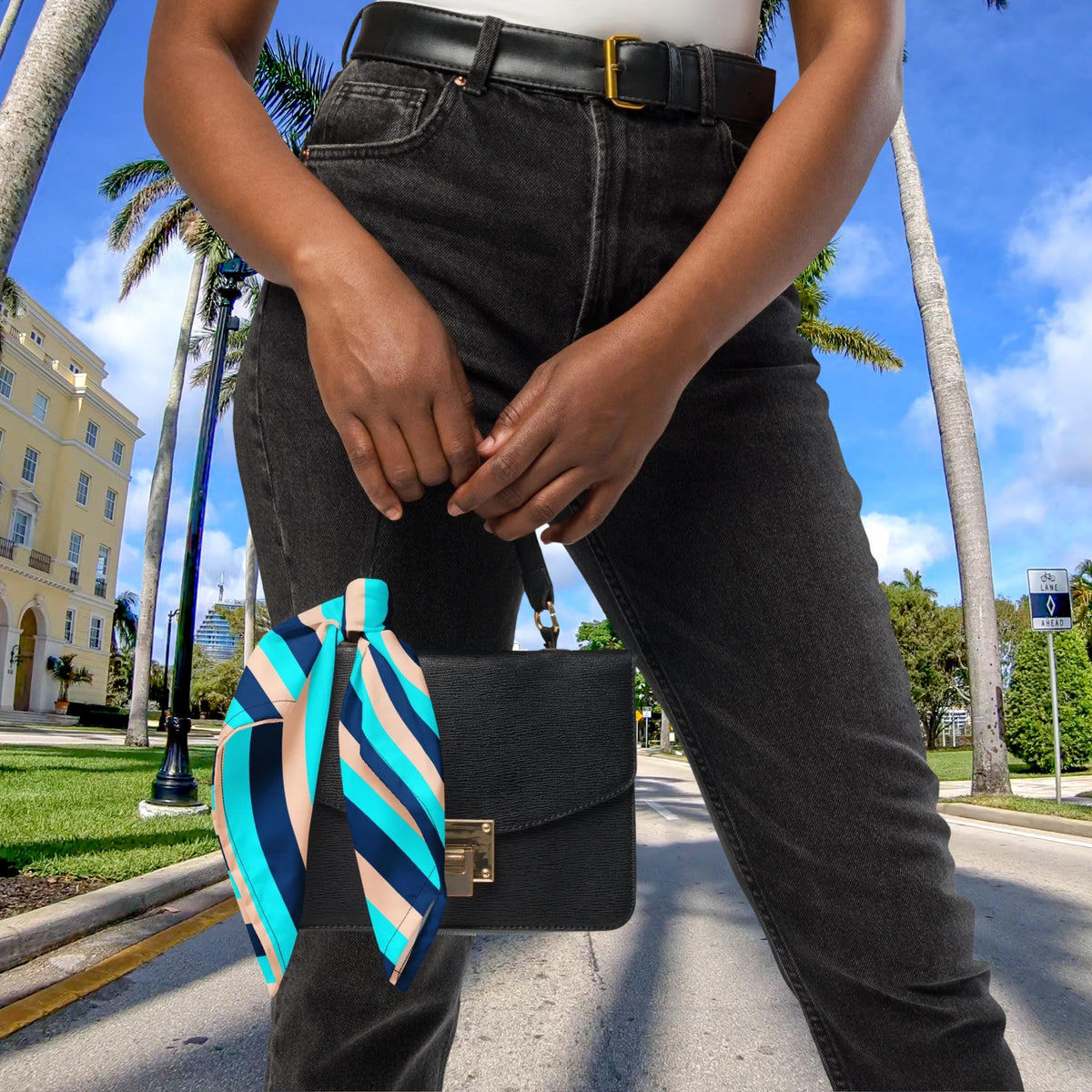 Blue Stripe bandana tied to the handle of a small black handbag.