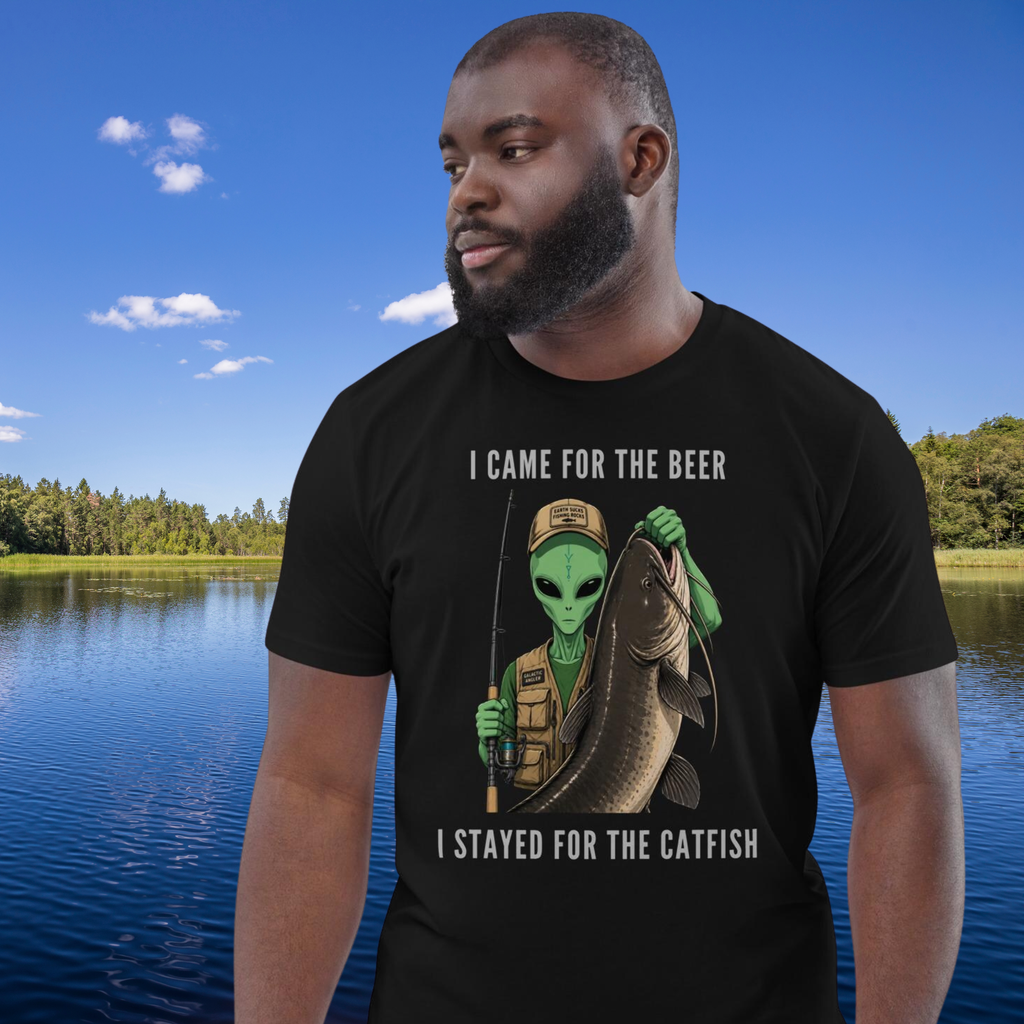 Alien Catfish fishing T-shirt in black, worn by a model against a blue lake backdrop.