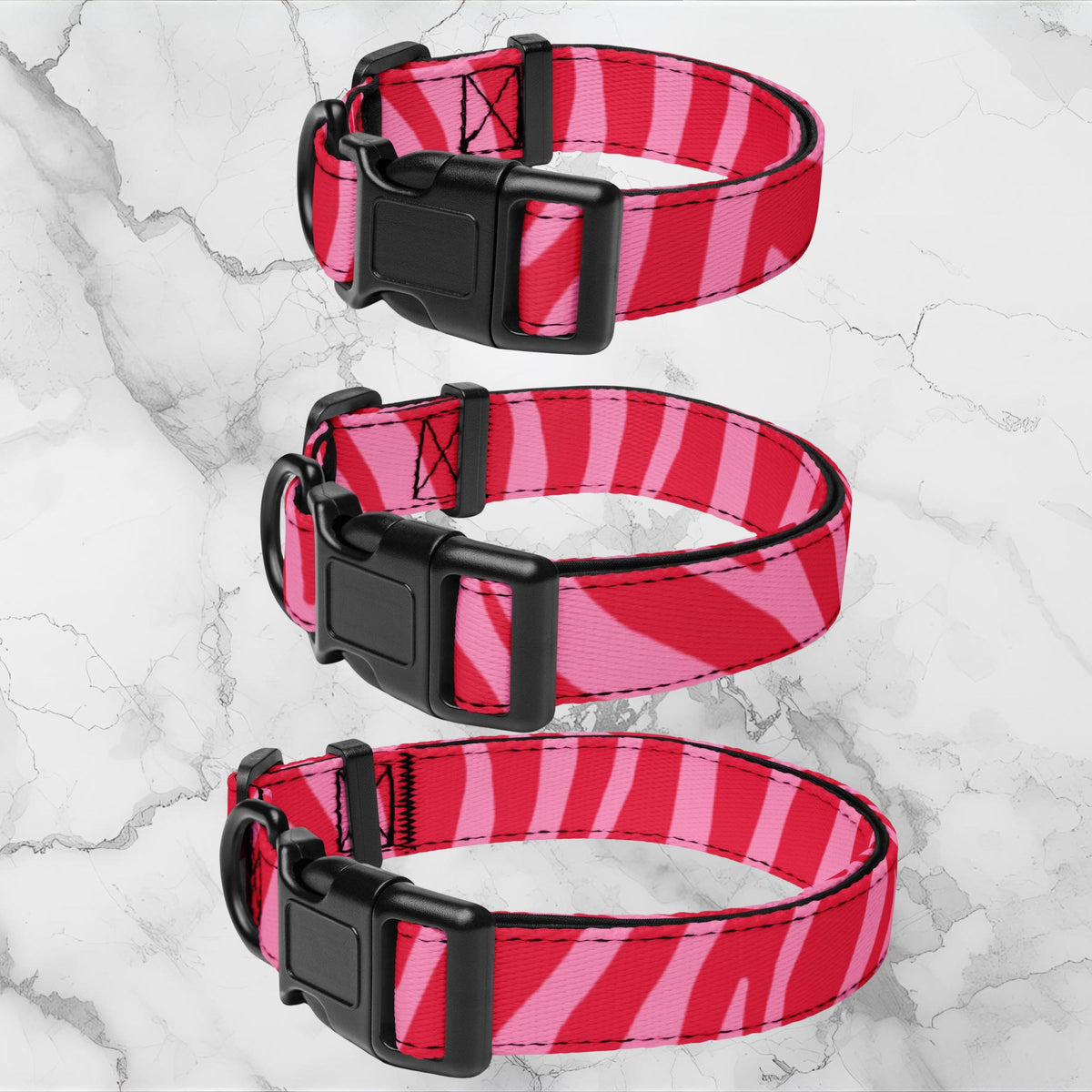 Pink Zebra padded dog collar three collar sizes displayed on a pale marble background.