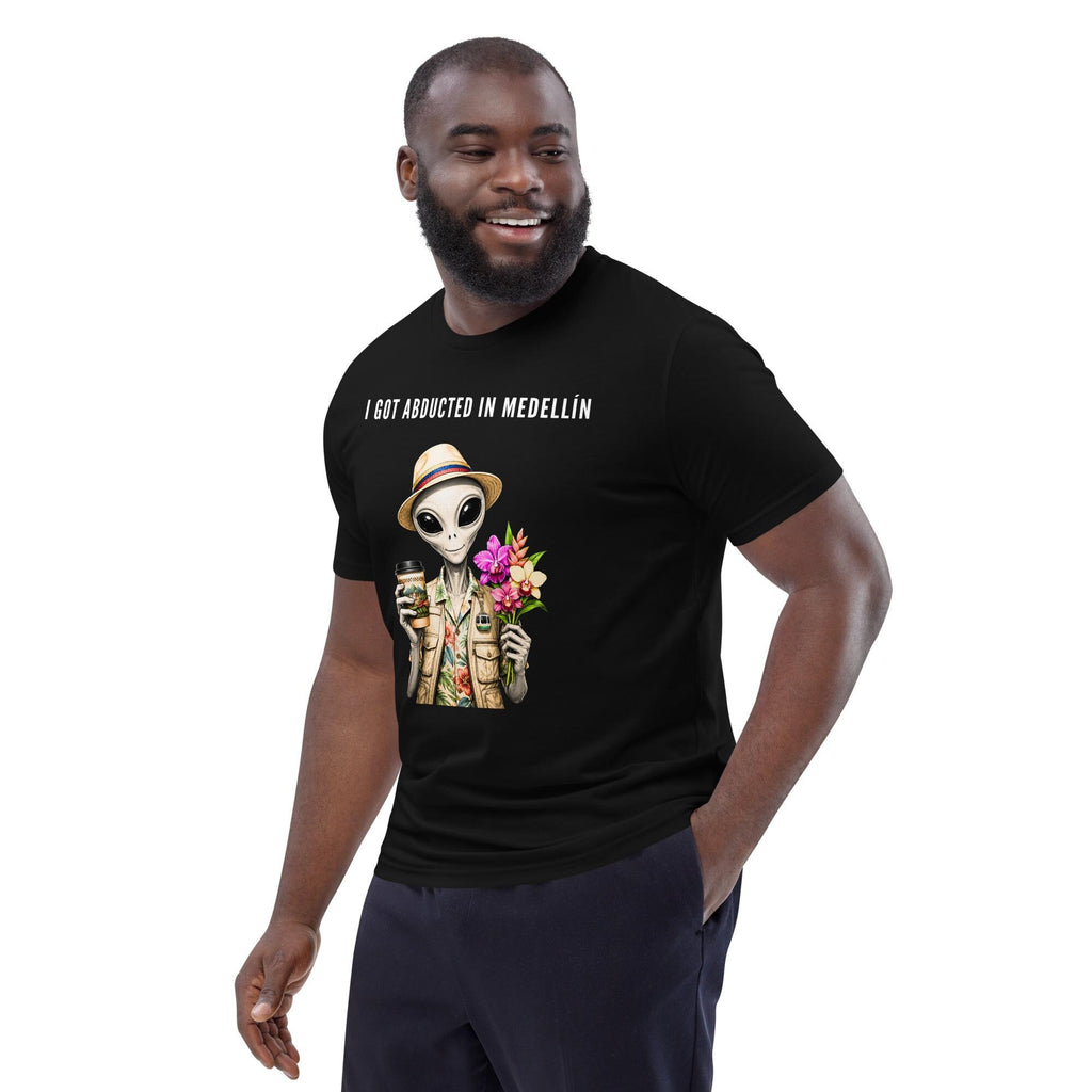 I Got Abducted in Medellin alien T-shirt in black, worn by a smiling model on white, three-quarter view.